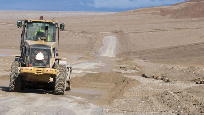 A NPS employee uses a loader to clear flood debris off Badwater Road. NPS/Giovanna Ponce