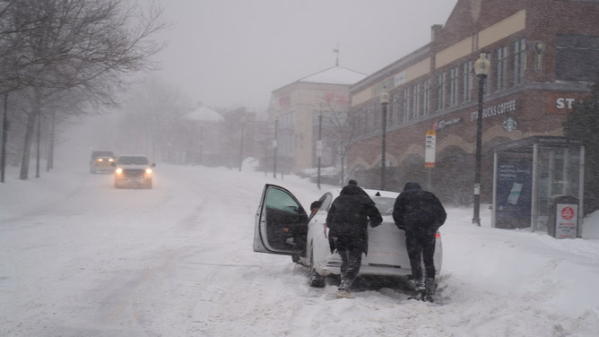 FILE - Residents help push a stuck car in Boston, Massachusetts on Saturday, Jan. 29, 2022. Photographer: Allison Dinner/Bloomberg via Getty Images