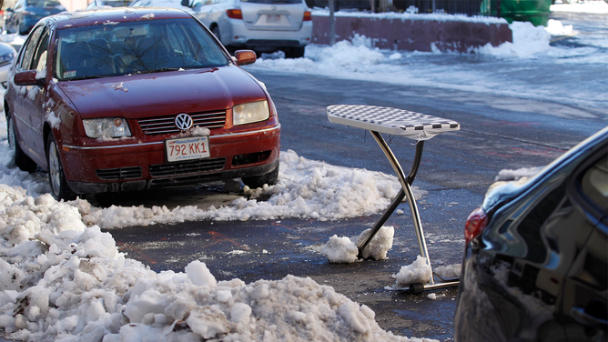 FILE - An ironing board is used as a space saver to claim a shoveled parking spot on East 4th Street in South Boston, Massachusetts on December 16, 2013, after the first snow storm of the season. (Photo by Jessica Rinaldi for The Boston Globe via Getty Images)