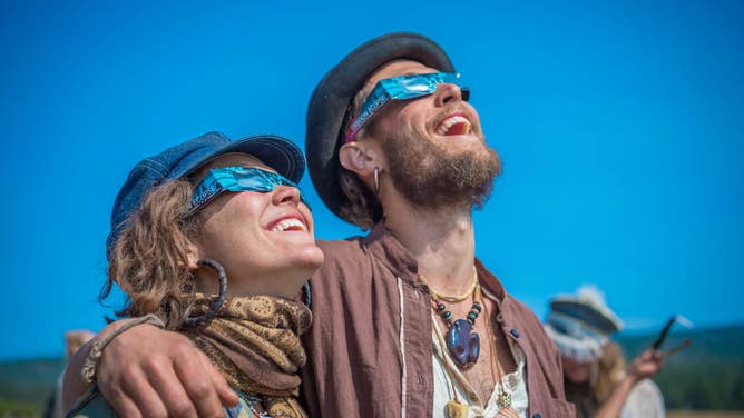 A couple look up at the sky to watch an eclipse.