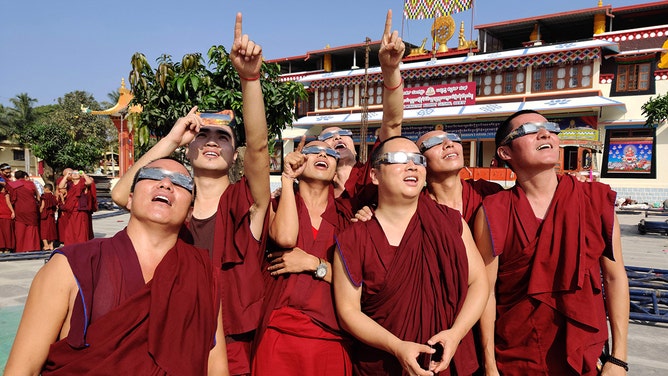 FILE -- Monks wearing solar filter glasses watch a "ring of fire" solar eclipse at the Gaden monastery in a Tibetan colony in Teginkoppa, 50km south of Dharwad in India's southern Karnataka state, on December 26, 2019.
