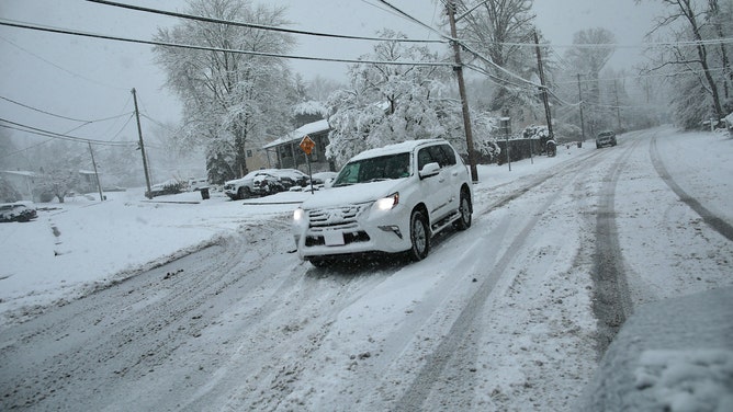 A car drives along Main Street as snow falls in Tappan, New York, on February 10, 2024.