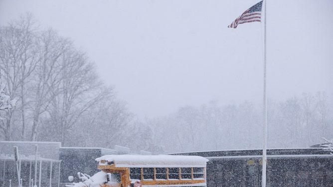 A school bus is covered in snow at the Northvale Public School in Northvale, New Jersey, on February 13, 2024.