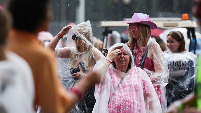 Fans of singer Taylor Swift, also known as a Swifties, shelter from the rain as they arrive for Swift's concert in Sydney on February 23, 2024.