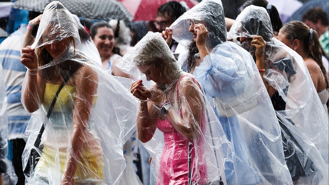 Fans of singer Taylor Swift, also known as a Swifties, shelter from the rain as they arrive for Swift's concert in Sydney on February 23, 2024.
