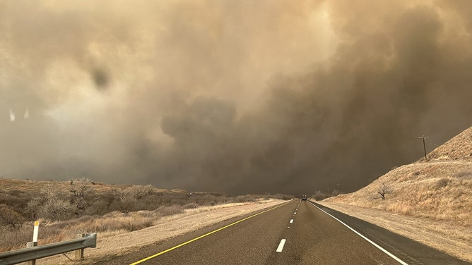 Smoke rises on the roadway in Hutchinson County after the Juliet Pass fire broke out in Armstrong County, Texas, on February 28, 2024.