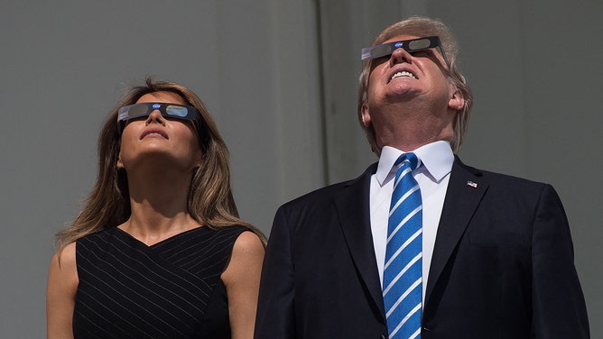 FILE -- President Donald Trump and First Lady Melania Trump look up at the partial solar eclipse from the balcony of the White House in Washington, DC, on August 21, 2017.