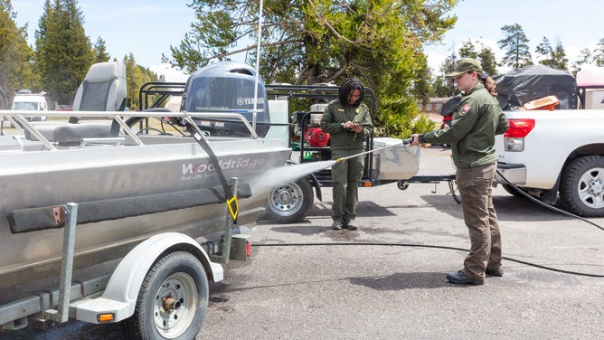 Aquatic invasive species technicians decontaminating a motorized boat and trailer.