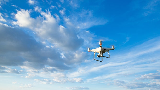 Drone flying overhead in cloudy blue sky