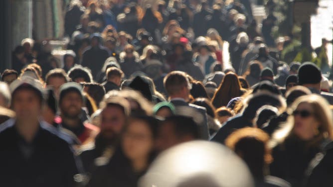 Crowd of people walking busy New York City street backlit