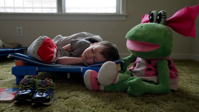 A 3-year-old boy naps on a cot at Our Loving Village in Stamford, Texas.