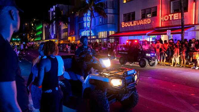 Police work to disperse a large crowd and reopen traffic on Ocean Drive during spring break on March 11, 2023, in Miami Beach, Florida.