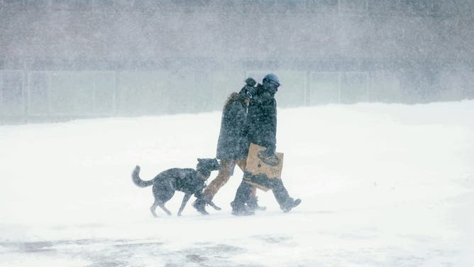 Two people walk with their dog as a blizzard hits Mammoth Lakes closing the mountain for skiers in the Eastern Sierra Nevadas of California, on March 2, 2024. The National Weather Service has issued a blizzard warning for California's entire Sierra Nevada through early March 3, 2024. Forecaster report the storm could bring three to five inches (8 to 13cms) of snow per hour. (Photo by DAVID SWANSON / AFP) (Photo by DAVID SWANSON/AFP via Getty Images)
