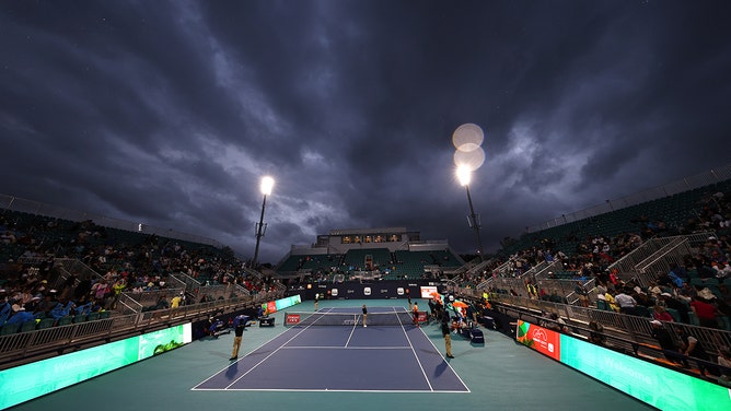 Denis Shapovalov of Canada and Stefanos Tsitsipas of Greece sit through a rain delay during their match on day 7 of the Miami Open at Hard Rock Stadium on March 22, 2024 in Miami Gardens, Florida.