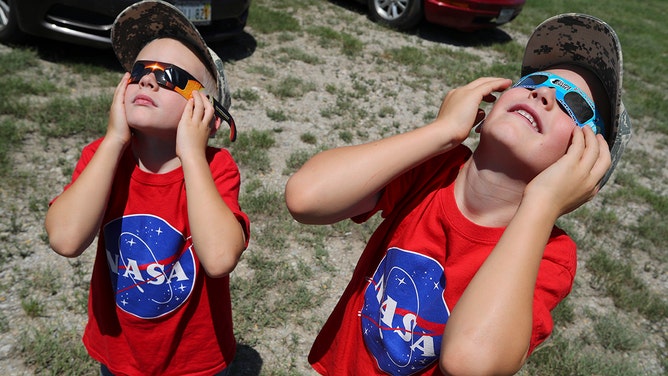 Two boys watch the solar eclipse at Texas Motor Speedway on August 21, 2017 in Fort Worth, Texas.