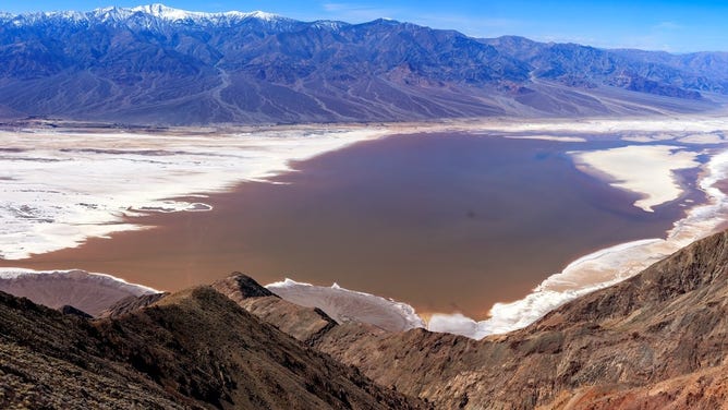 Photo taken March 4, 2024 from Dantes View looking down at Badwater Basin. Lake Manly has returned to the pre-wind location, but is now very brown due to mud. NPS/John Hallett