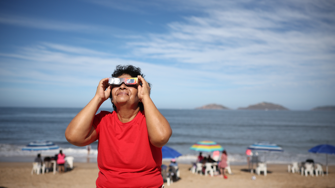 MAZATLAN, MEXICO - APRIL 08: A woman puts on her glasses to see the eclipse on April 08, 2024 in Mazatlan, Mexico. Millions of people have flocked to areas across North America that are in the "path of totality" in order to experience a total solar eclipse. During the event, the moon will pass in between the sun and the Earth, appearing to block the sun. (Photo by Hector Vivas/Getty Images)