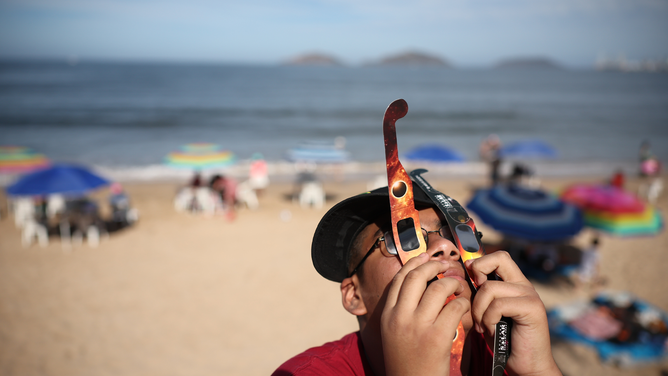 MAZATLAN, MEXICO - APRIL 08: A person uses two sets of glasses to see the eclipse on April 08, 2024 in Mazatlan, Mexico. Millions of people have flocked to areas across North America that are in the "path of totality" in order to experience a total solar eclipse. During the event, the moon will pass in between the sun and the Earth, appearing to block the sun. (Photo by Hector Vivas/Getty Images)