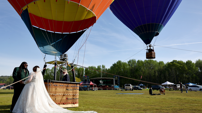 RUSSELLVILLE, ARKANSAS - APRIL 08: Bride and groom Kylee and Michael Rice prepare to take a hot air balloon ride before a planned mass wedding of over 200 couples at the Total Eclipse of the Heart festival on April 8, 2024 in Russellville, Arkansas. Millions of people have flocked to areas across North America that are in the "path of totality" in order to experience a total solar eclipse. During the event, the moon will pass in between the sun and the Earth, appearing to block the sun. (Photo by Mario Tama/Getty Images)