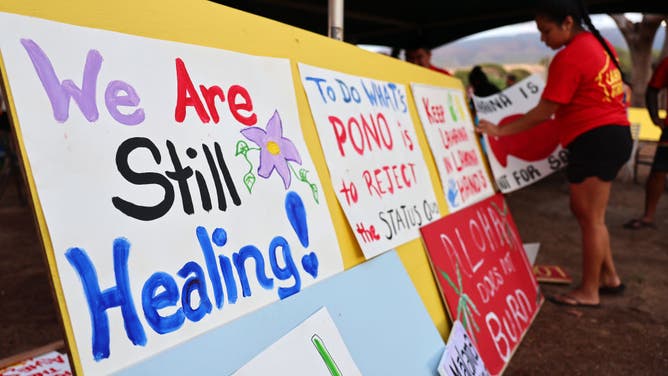 A community member hangs a sign at a 'Lahaina Strong' gathering on October 6, 2023 in Lahaina, Hawaii. Community members painted signs expressing their opposition to the October 8th start of tourists returning to west Maui following the devastating wildfire.