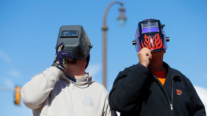 Oklahoma State Cowboys fans watch the solar eclipse through a welding helmet before a game against the Kansas Jayhawks at Boone Pickens Stadium on October 14, 2023 in Stillwater, Oklahoma.