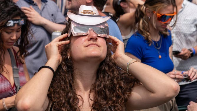 A woman looks up at the sun through protective eyewear during a solar eclipse in Austin, Texas on April 8, 2024.