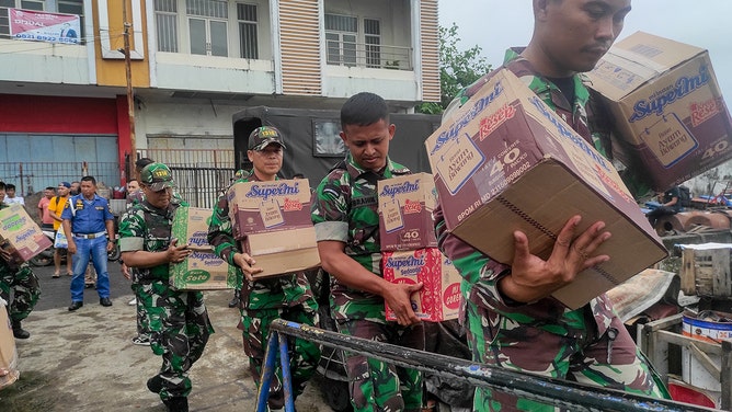 Indonesian military personnel load food items onto a ship as they head to the island near Mount Ruang volcano at the port in Manado, North Sulawesi, on April 18, 2024