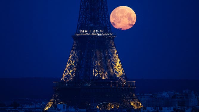 This photograph taken in Paris on April 23, 2024, shows the April's full moonset, also known as the Pink Moon, seen behind the Eiffel Tower. 