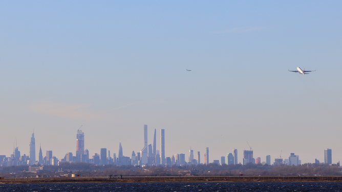 A passenger aircraft takes off from JFK international Airport in New York as the Manhattan skyline looms in the distance on February 5, 2024. (Photo by Charly TRIBALLEAU / AFP) (Photo by CHARLY TRIBALLEAU/AFP via Getty Images)