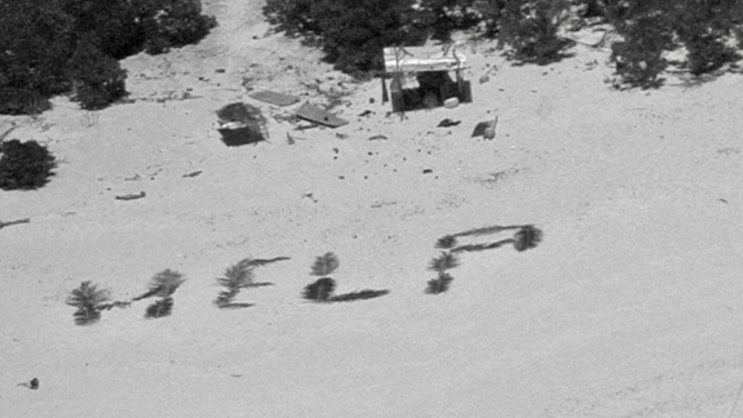 This image shows the word "HELP" written on the beach of a remote island in the Pacific Ocean.