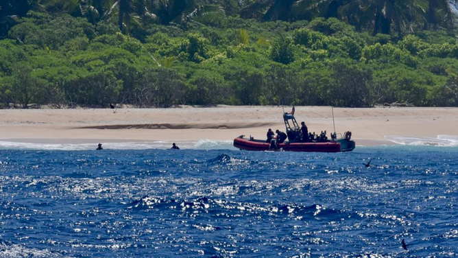 The image shows the U.S. Coast Guard near the beach of a remote Pacific island where the stranded sailors were rescued.