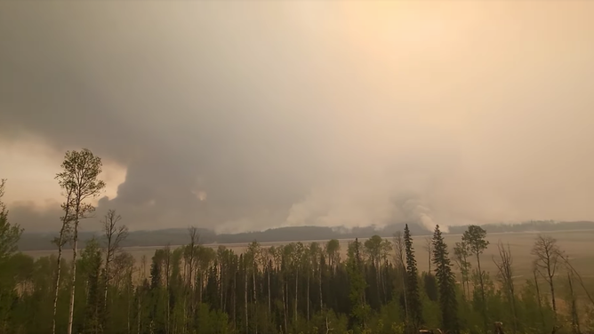A yellow-looking sky is seen as smoke rises from mountains surrounding Fort Nelson, in British Columbia. An evacuation order was issued for the Fort Nelson area as wildfires were threatening the community.