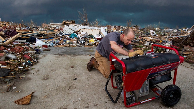 With storm clouds looming overhead, Stewart Munson, of St. Louis, Missouri, checked to see if his sister's generator could be salvaged, Monday, May 23, 2011, after a tornado swept through the heart of the city on Sunday in Joplin, Missouri.