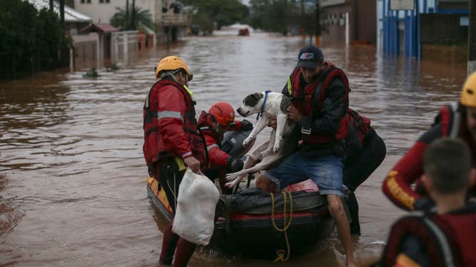 Firefighters rescue a man and his dog from a flooded area at the city center of Sao Sebastiao do Cai, Rio Grande do Sul state, Brazil on May 2, 2024.