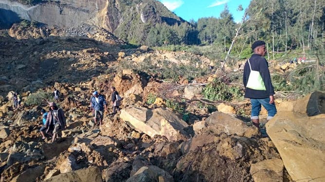 People gather at the site of a landslide in Maip Mulitaka in Papua New Guinea's Enga Province on May 24, 2024. Local officials and aid groups said a massive landslide struck a village in Papua New Guinea's highlands on May 24, with many feared dead.