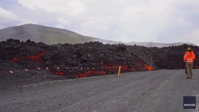 This image captured from a video recorded by Marco Di Marco shows red-hot lava flowing over a main road to and from the evacuated town of Grindavik in Iceland after a volcanic eruption that began at the end of May 2024.