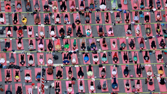 Thousands of yoga practitioners flock to New York Times Square to celebrate the summer equinox and over twenty years of all-day yoga event.