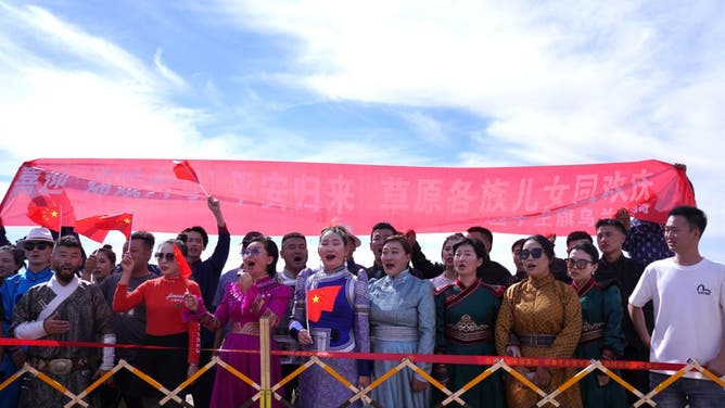 People wearing traditional clothing cheer as the landing module of the Chang'e-6 moon probe is recovered after it landed in Inner Mongolia, in northern China on June 25, 2024.