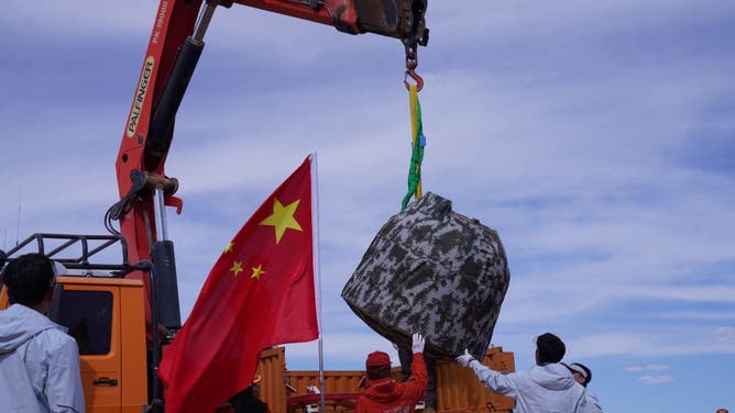 Officials load the landing module of the Chang'e-6 moon probe onto a truck after it landed in Inner Mongolia, in northern China on June 25, 2024.