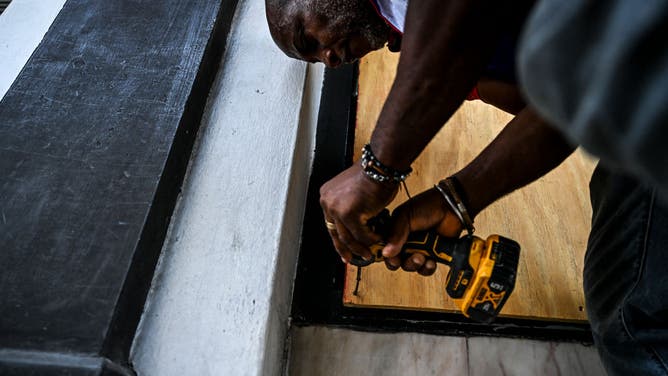 A man screws a board onto the window of a shop in preparation for the arrival of Hurricane Beryl in Bridgetown, Barbados on June 30, 2024. Beryl, the first hurricane of the 2024 Atlantic season, strengthened into an "extremely dangerous" Category 4 storm Sunday as it threatened the southeast Caribbean with potentially life-threatening winds and storm surge, US trackers said.