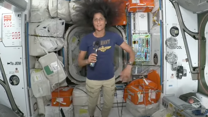 NASA astronaut Suni Williams on the International Space Station wearing a "Fly Navy" t-shirt.