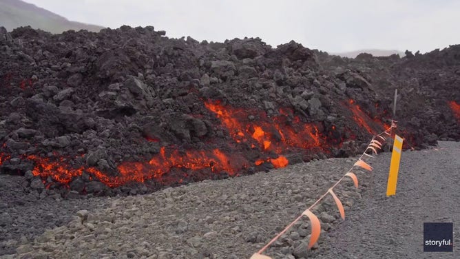 This image captured from a video recorded by Marco Di Marco shows red-hot lava flowing over a main road to and from the evacuated town of Grindavik in Iceland after a volcanic eruption that began at the end of May 2024.