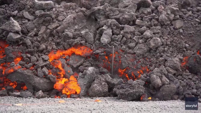 This image captured from a video recorded by Marco Di Marco shows red-hot lava flowing over a main road to and from the evacuated town of Grindavik in Iceland after a volcanic eruption that began at the end of May 2024.