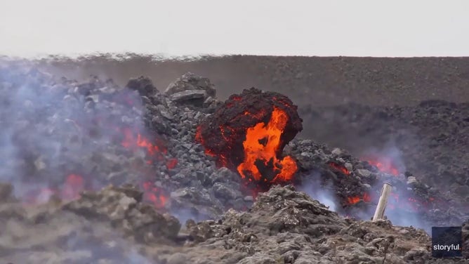 This image captured from a video recorded by Marco Di Marco shows red-hot lava flowing over a main road to and from the evacuated town of Grindavik in Iceland after a volcanic eruption that began at the end of May 2024.