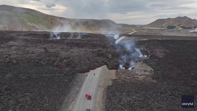 This image captured from a video recorded by Marco Di Marco shows red-hot lava flowing over a main road to and from the evacuated town of Grindavik in Iceland after a volcanic eruption that began at the end of May 2024.