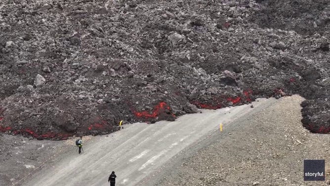 This image captured from a video recorded by Marco Di Marco shows red-hot lava flowing over a main road to and from the evacuated town of Grindavik in Iceland after a volcanic eruption that began at the end of May 2024.