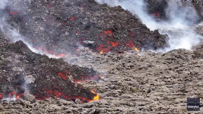 This image captured from a video recorded by Marco Di Marco shows red-hot lava flowing over a main road to and from the evacuated town of Grindavik in Iceland after a volcanic eruption that began at the end of May 2024.