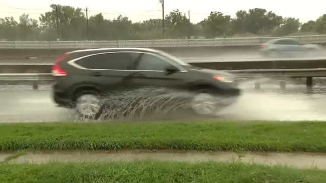 Water splashes as a car travels along Interstate 45 in Houston on July 26, 2024.