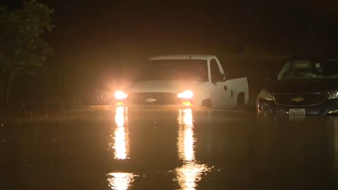 A vehicle navigates a flooded roadway in Baytown, Texas, on July 26, 2024.