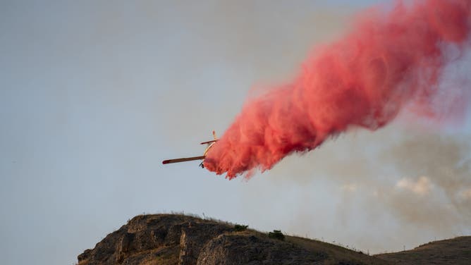 This image shows an airplane dropping fire retardant over the Sandhurst Fire burning outside Salt Lake City on Saturday, July 20, 2024.